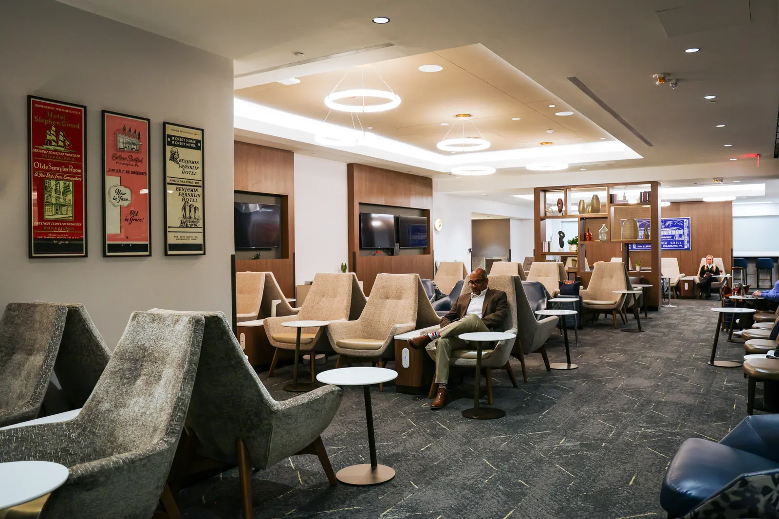 Beige high-back lounge chairs under ring chandeliers in the renovated Delta Sky Club at Philadelphia (PHL).
