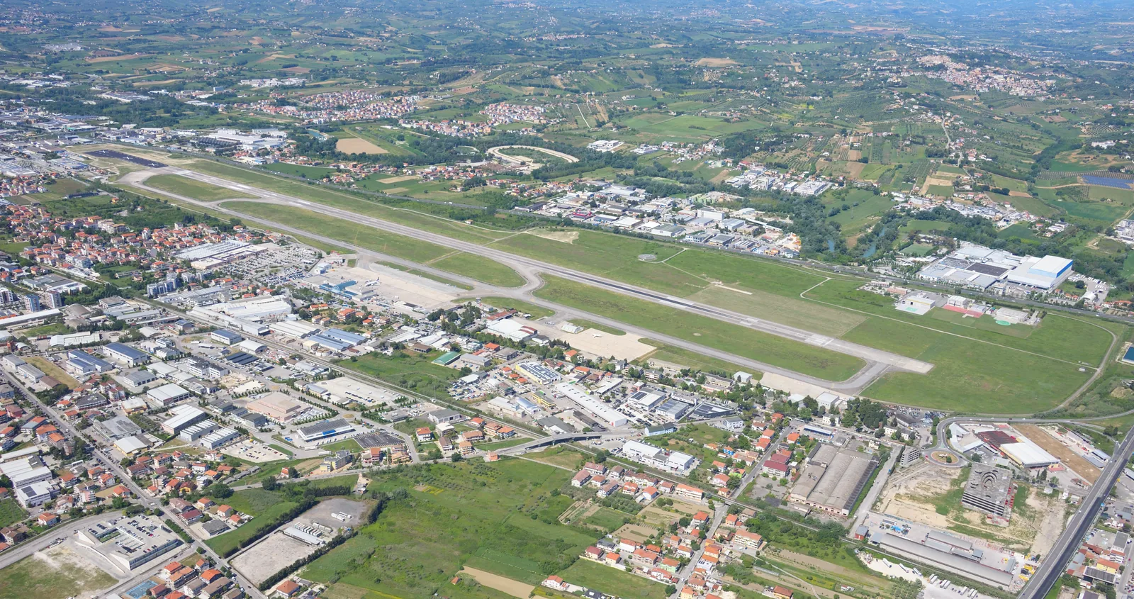 Aerial view of Abruzzo Airport in Pescara with the single runway, apron and terminal between the city's suburbs