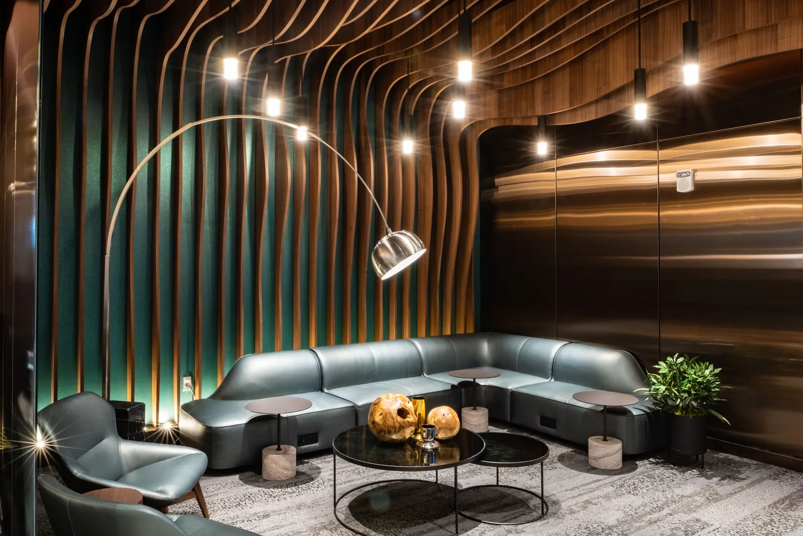 Grey sectional seating under undulating wood-slat ceiling with pendant lights in the Delta One Lounge at Seattle-Tacoma (SEA).