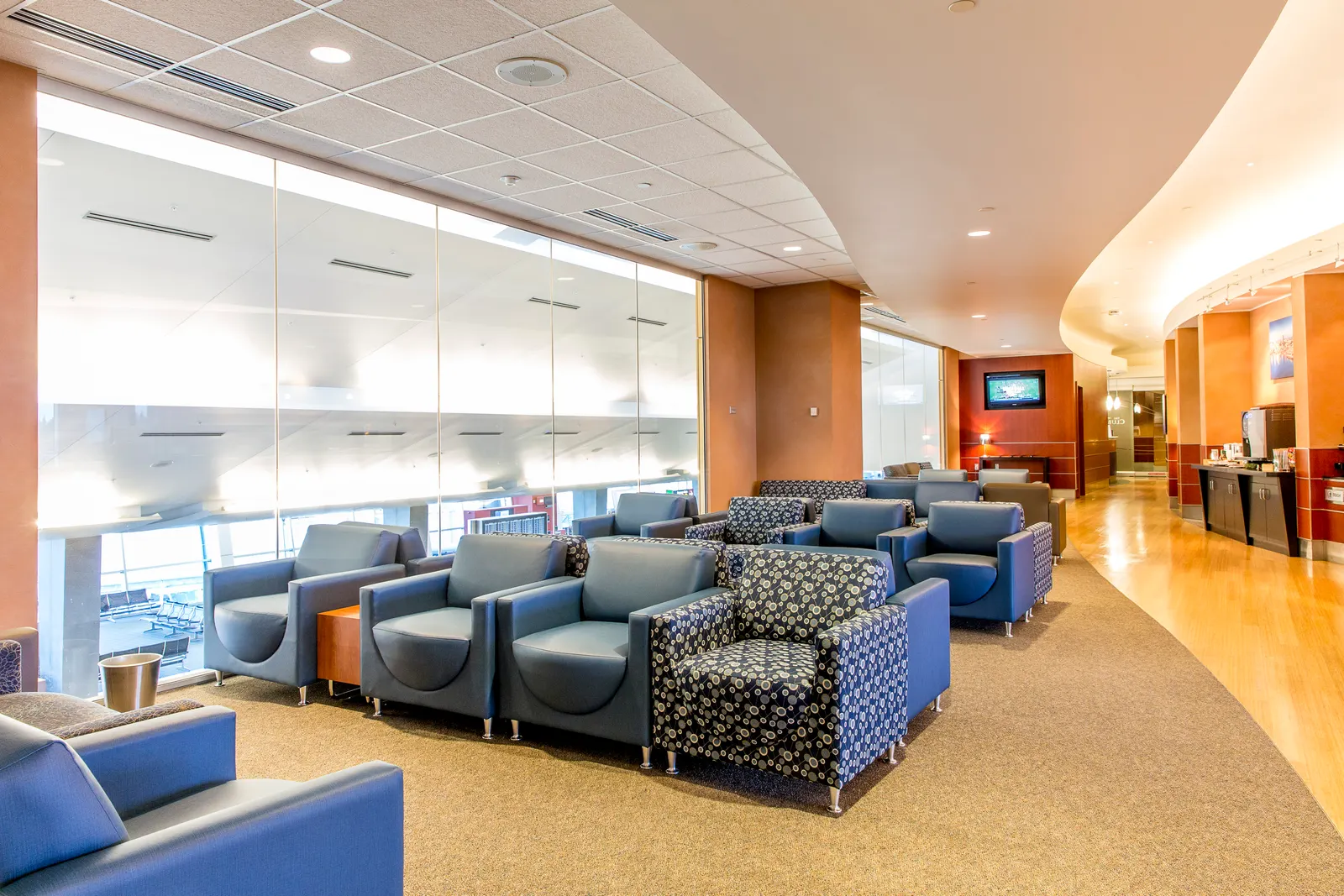 Armchairs and side tables in a bright seating area of The Club at SEA Concourse A.