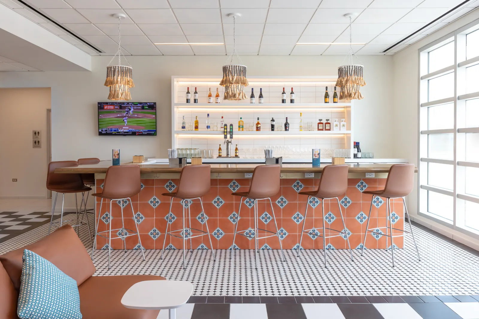Tiled bar with stools and woven pendant lights in the Escape Lounge at Luis Muñoz Marín International Airport (SJU).