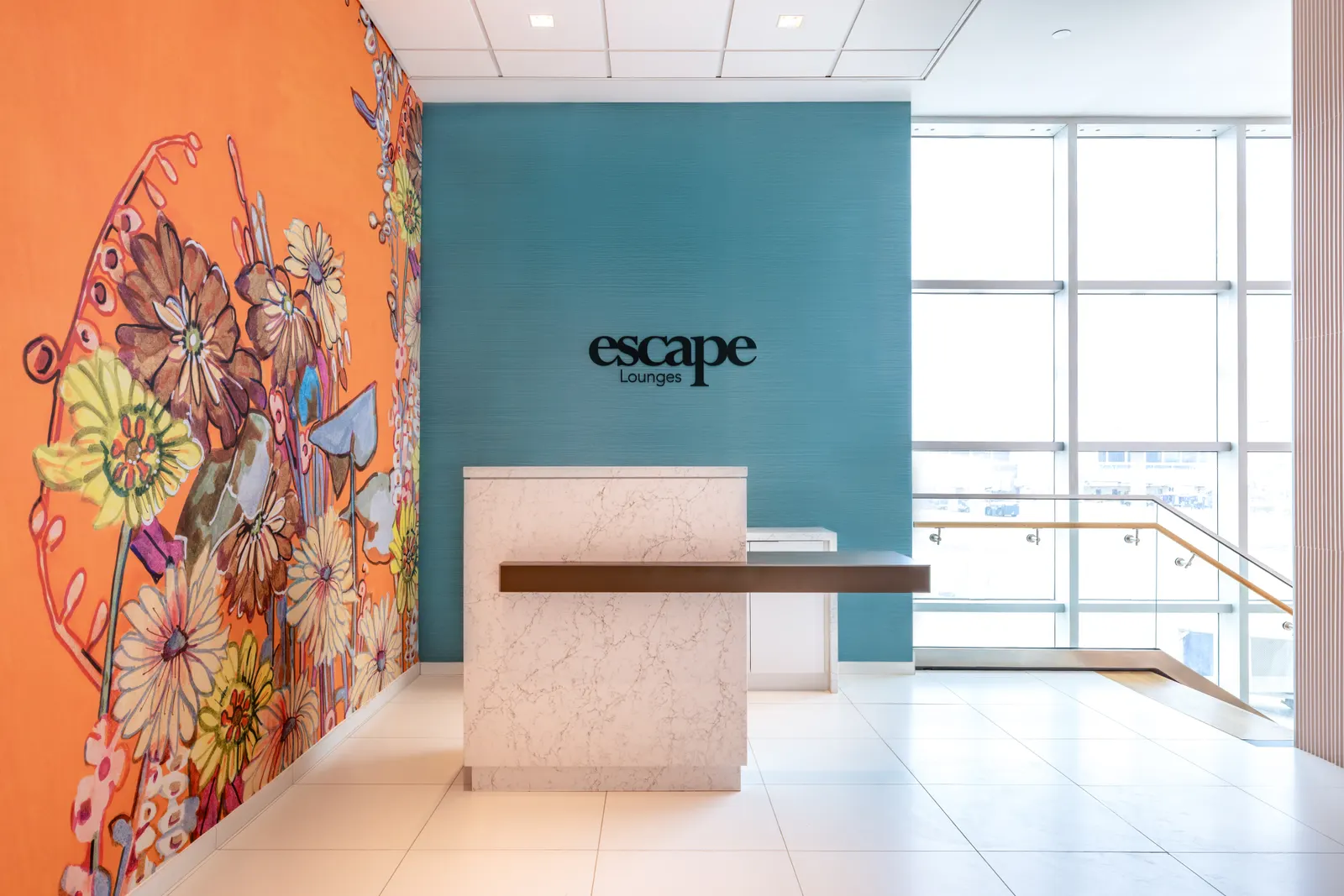 Reception desk, Escape Lounges logo and floral mural at Luis Muñoz Marín International Airport (SJU).