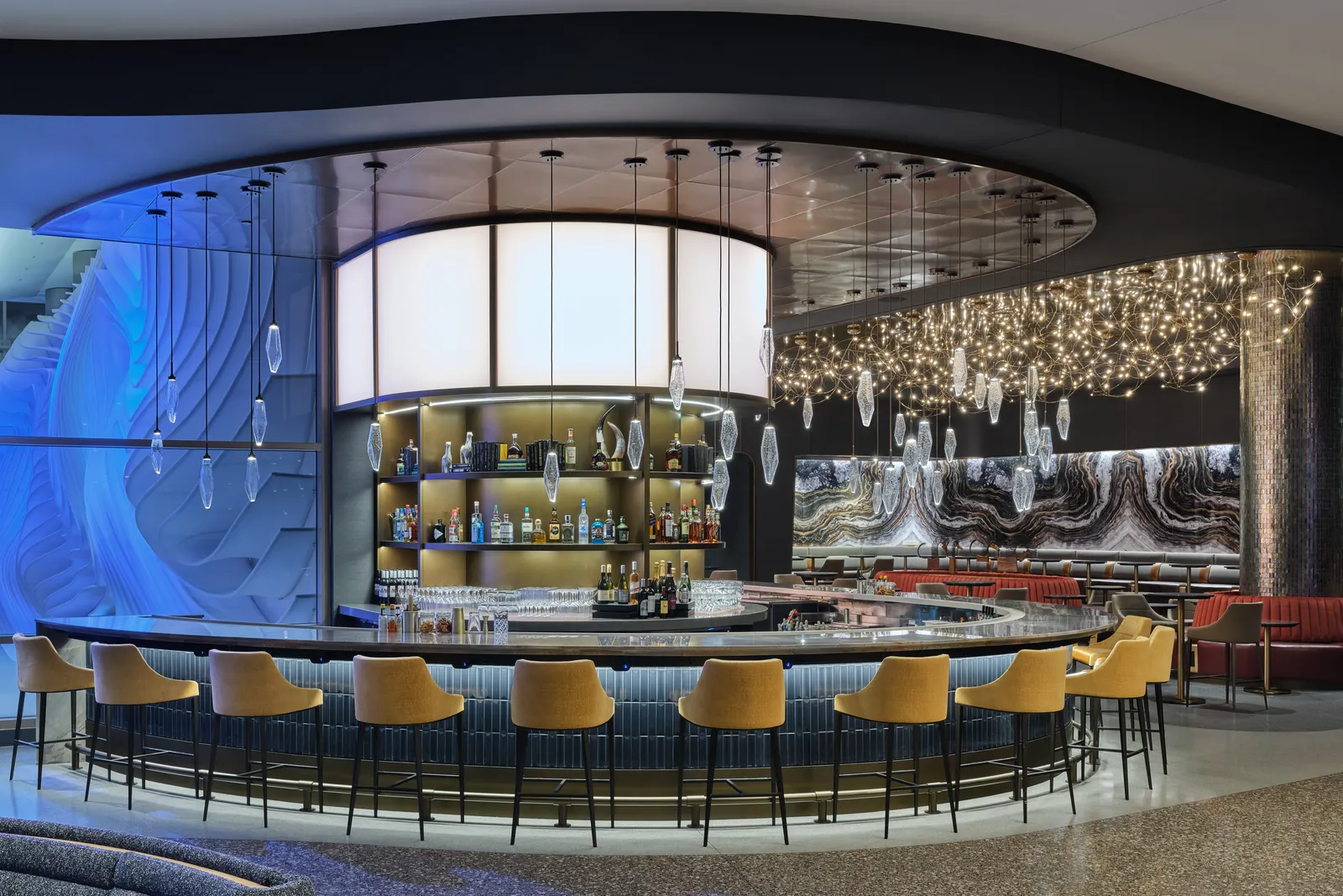 Circular wrap-around bar with mustard velvet stools and teardrop pendants in the Delta Sky Club at Salt Lake City Concourse B (SLC).