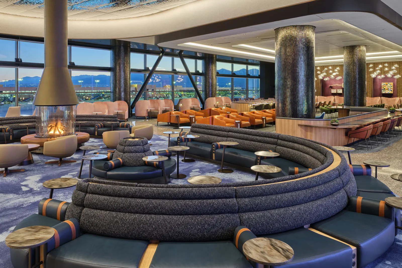 The lounge interior features a geometric ceiling, terrazzo flooring, wood finishes, and copper-toned details.