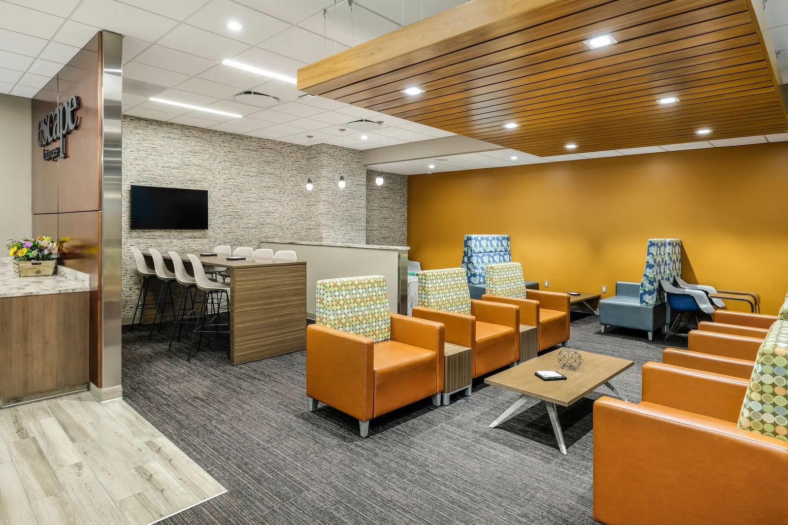 Orange and patterned armchairs around low tables in Escape Lounges Terminal A at Sacramento International Airport (SMF).
