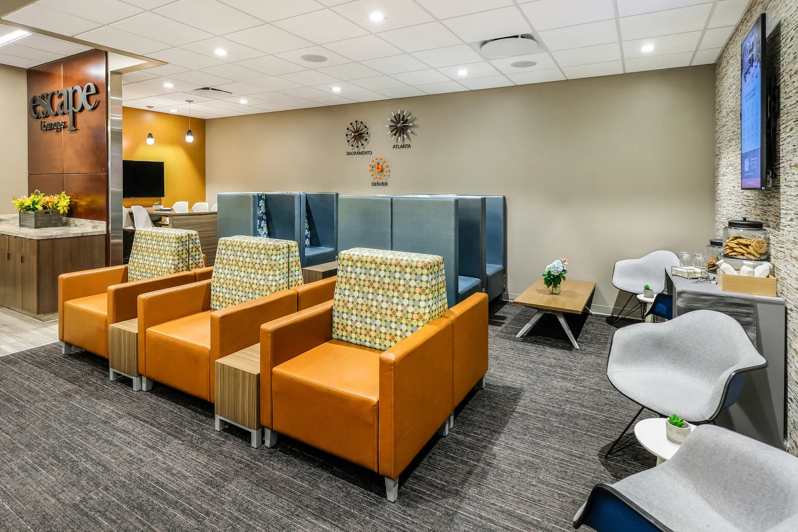 Rows of orange armchairs with side tables in Escape Lounges Terminal B at Sacramento International Airport (SMF).
