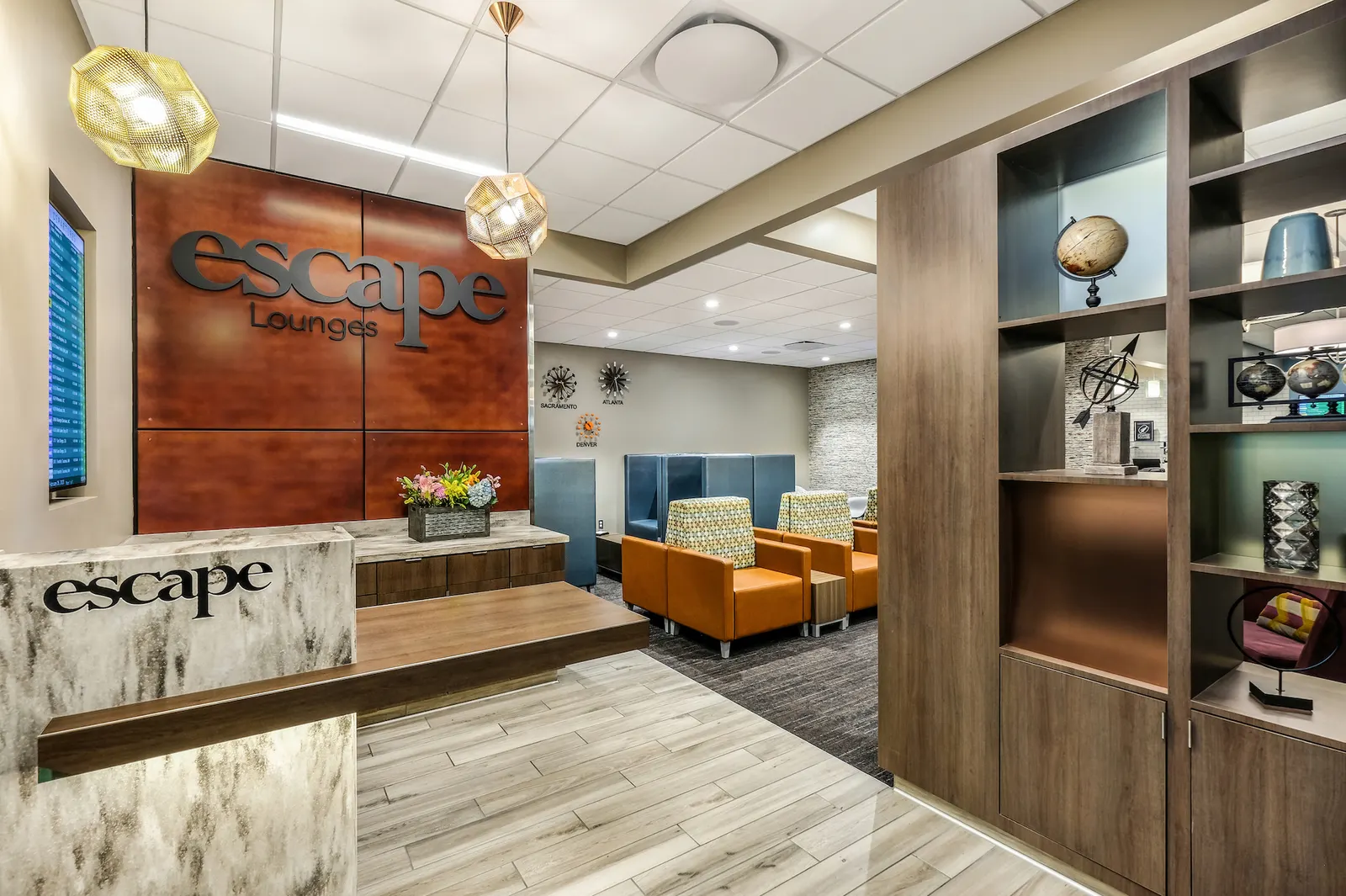 Reception desk, logo wall and seating beyond in Escape Lounges Terminal B at Sacramento International Airport (SMF).