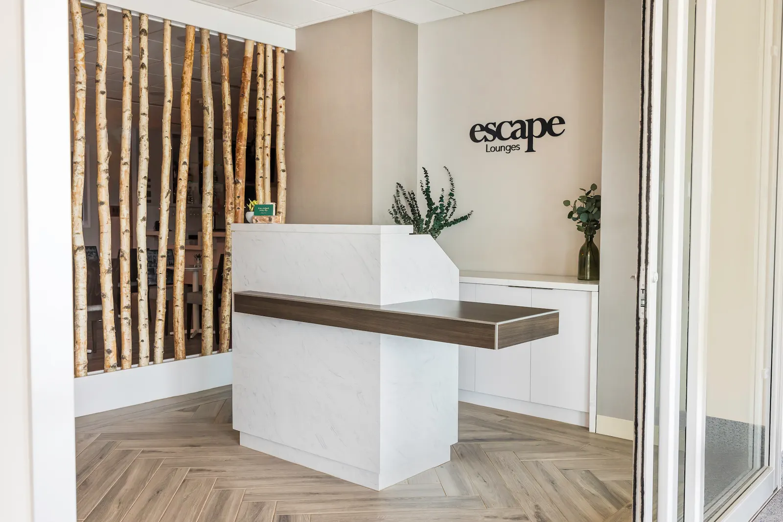 White reception desk and Escape Lounges logo wall at Syracuse Hancock International Airport (SYR).