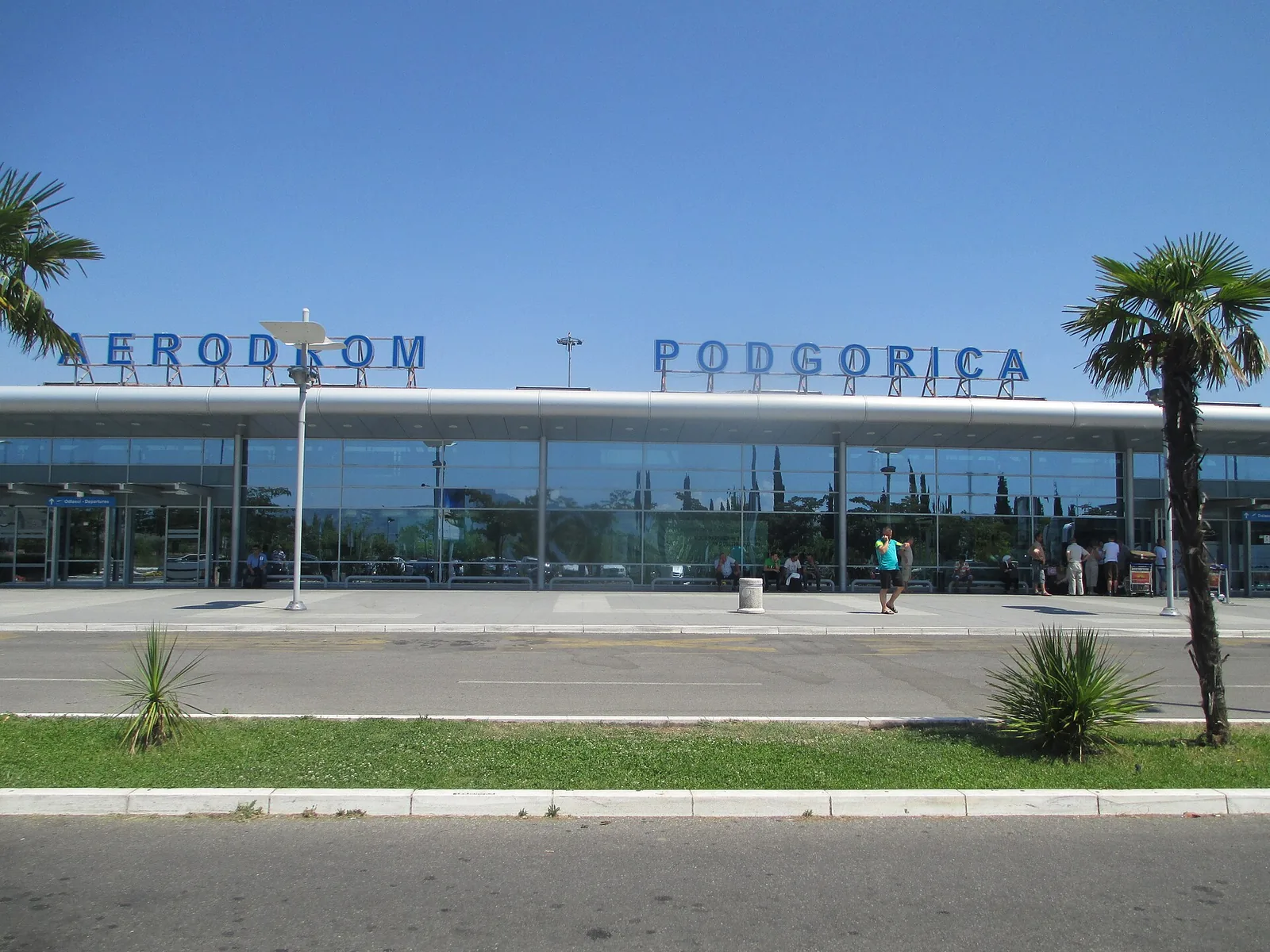 Landside façade of the Podgorica Airport passenger terminal with AERODROM PODGORICA lettering and palm trees, July 2014