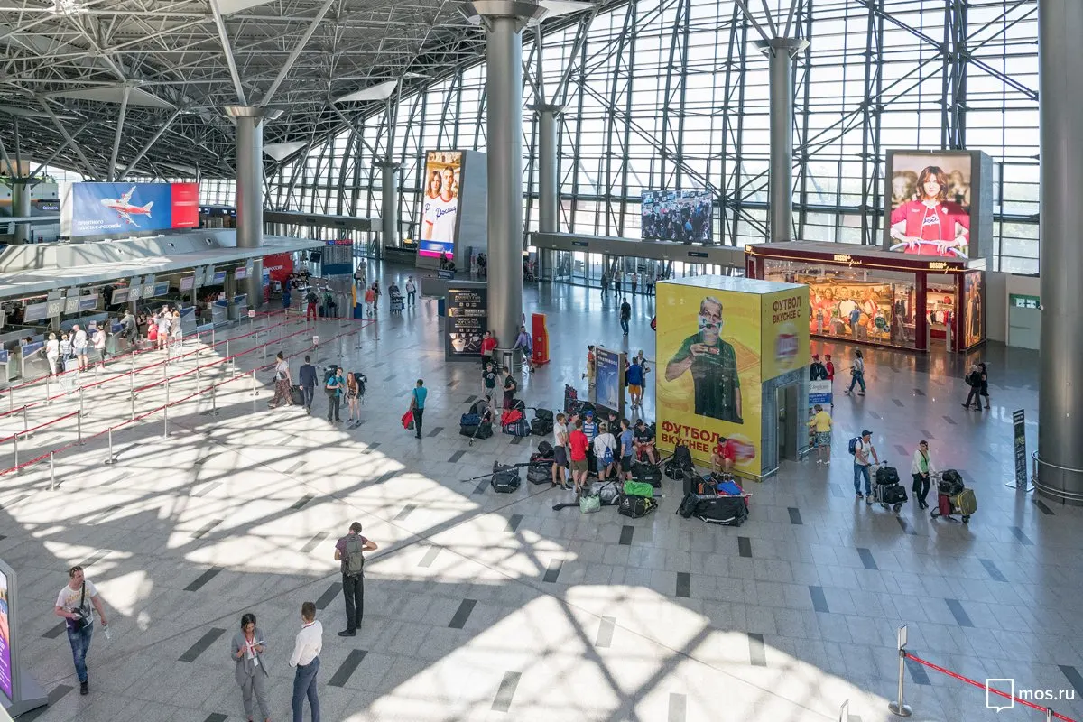 Overhead view of Terminal A check-in hall with glass roof, shop cube and passengers.