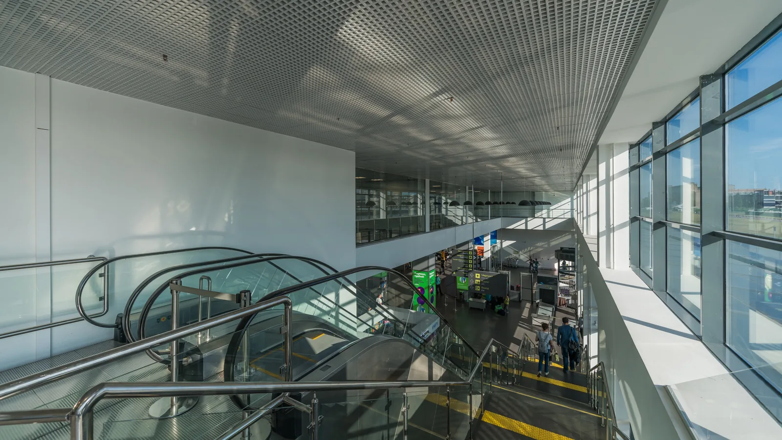 Bright two-level interior of the Zhukovsky passenger terminal with escalators, glass façade and seating